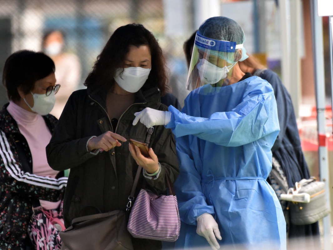  4月19日，在香港旺角流动采样站，工作人员指导市民做核酸检测。新华社 图