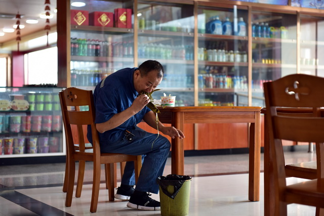 川成都一家运输公司货车司机邹洪彬在高速公路服务司吃粽子，这就是他的午饭。摄影/章轲
