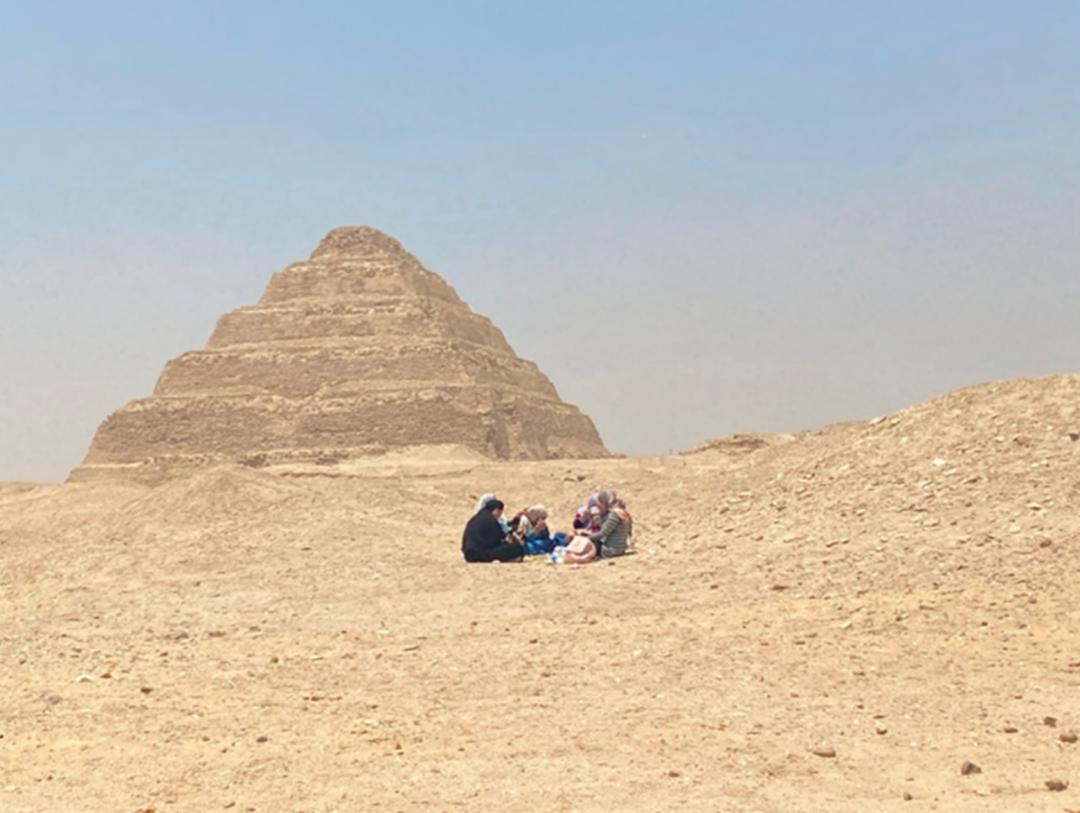 在埃及阶梯金字塔前郊游野餐的当地女性。