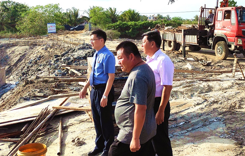 陵水县检察院检察长邹志云（左一）前往施工现场，与三才镇政府负责人及施工方负责人交谈征地及施工情况。