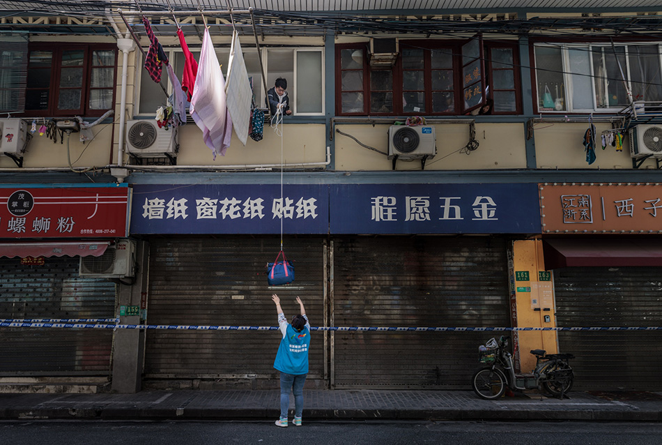 2022年3月29日,上海,志愿者通过绳子向一名被隔离的市民传递生活物资。澎湃影像 图