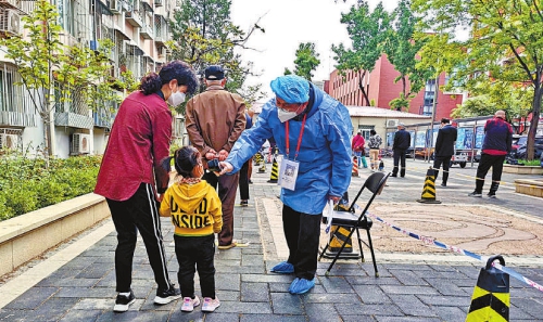 在核酸检测现场,北京市石景山区检察院干警为群众测量体温。记者闫昭 通讯员成于庆摄