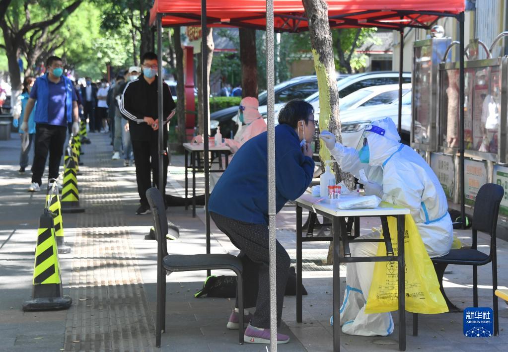 5月16日，在北京市海淀区中关村街道东里南社区临时核酸检测采样点，医务人员为市民进行核酸采样。新华社记者 任超 摄