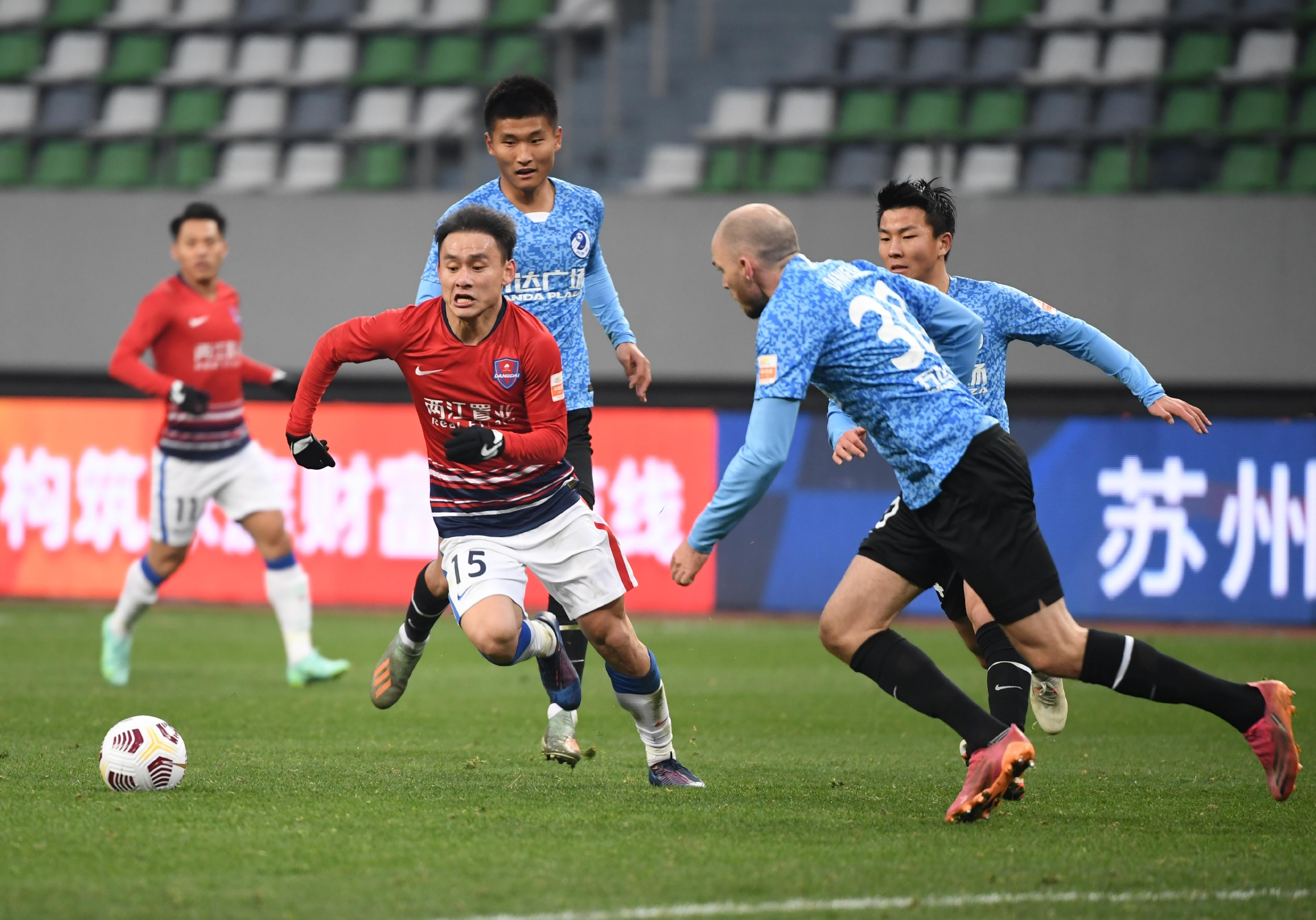 去年12月28日，重庆（红衣）和大连两队球员在比赛中拼抢。  图/新华社