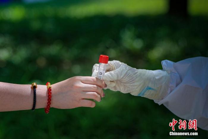 圖爲5月22日,一位北京市民將自己的病毒採樣管交給採樣人員。 中新社記者 賈天勇 攝