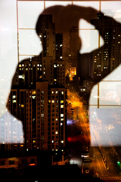 2020年3月8日晚，济南，一位摄影师居家隔离时对着窗户拍摄的自拍像。视觉中国供图