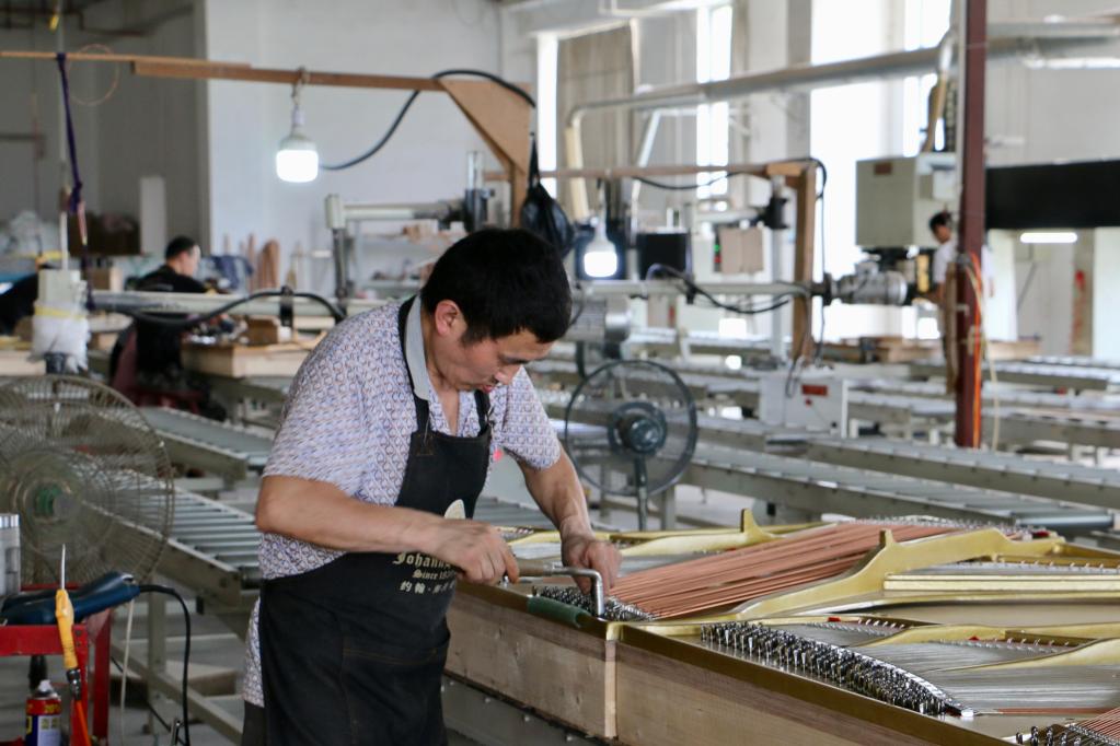 6月21日,东衡村钢琴众创园的工人在为钢琴挂弦。新华社记者 王聿昊 摄
