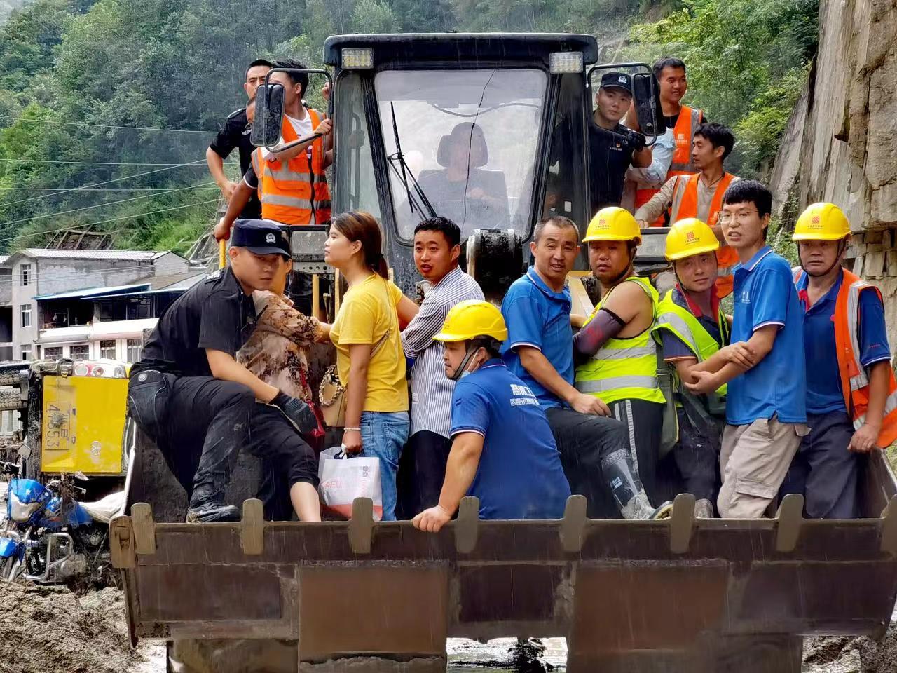 公安民警和消防等救援人員一起,乘坐推土機進入受災嚴重的區域,成功將被困羣衆轉移出來。