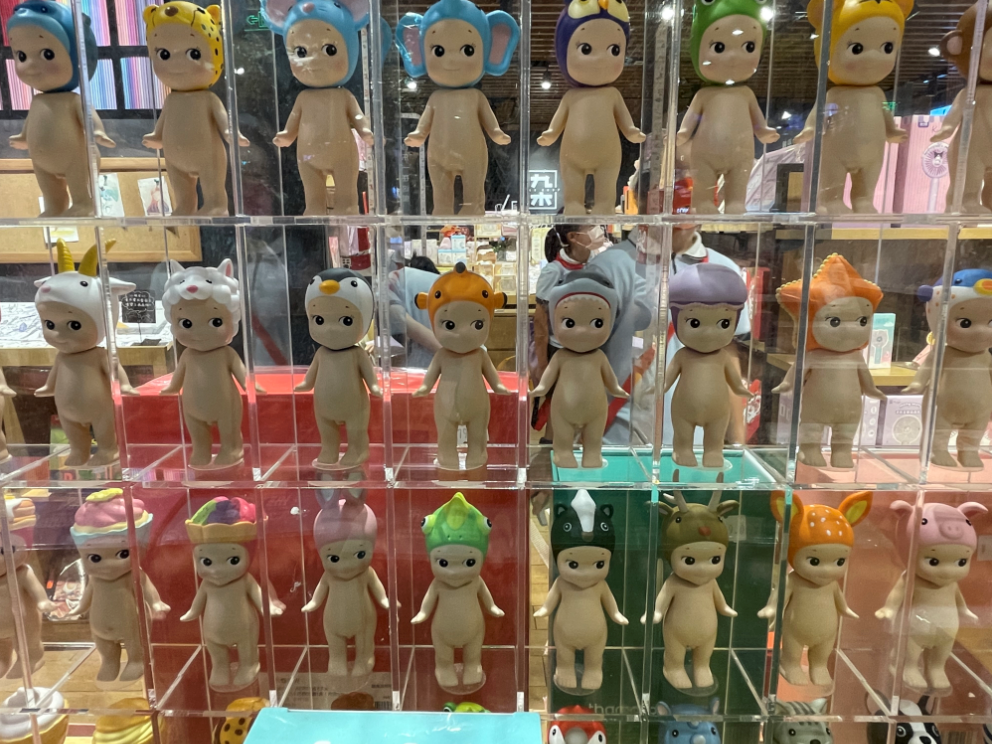 九木杂物社(环宇荟店)内,一整面墙裸体娃娃货架,与文具区域紧邻