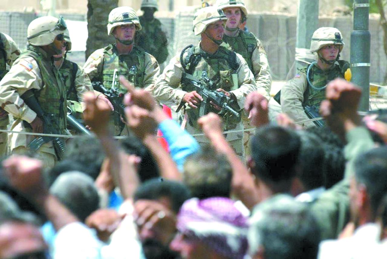 ▲当地时间2003年6月18日，美军士兵在伊拉克首都巴格达持枪面对示威的伊拉克人。图/新华社