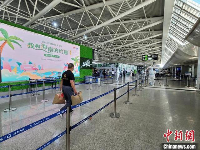 三亞鳳凰國際機場,踏上返程之旅的滯留旅客走過一面LED屏幕。 王曉斌 攝