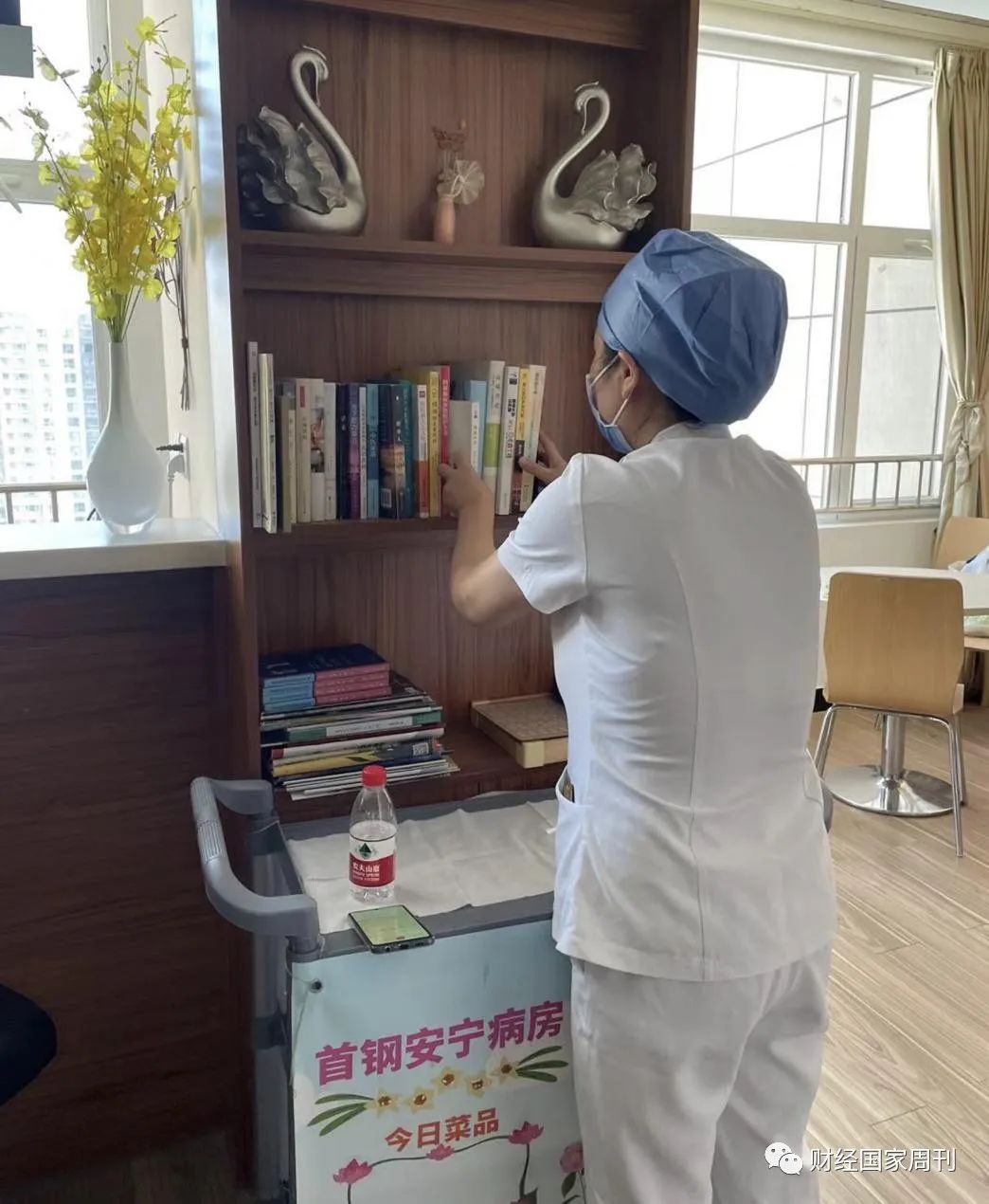 ▲北大首钢医院安宁疗护中心护士长孙文喜正在整理谈心室的图书角。图/财经国家周刊 张曙霞 摄