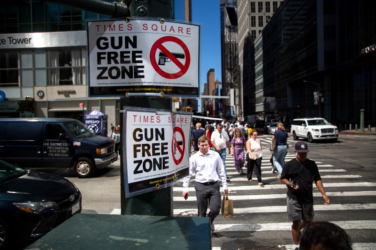 9月1日，人们从美国纽约时报广场邻近街区的“禁枪区”标志牌旁走过。