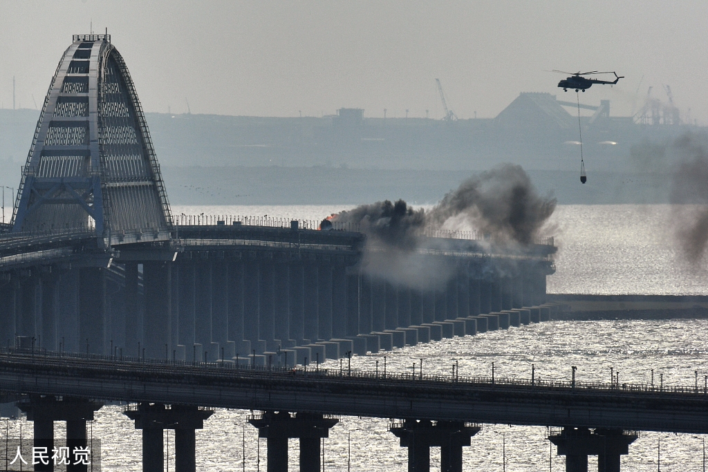 当地时间2022年10月8日，克里米亚，一架直升机在刻赤海峡上连接俄罗斯大陆和克里米亚半岛的克里米亚大桥上洒水灭火。人民视觉 图