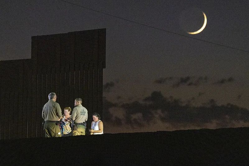 当地时间2022年9月27日，美国亚利桑那州，边境巡逻人员在边境围栏附近处理移民。图/视觉中国