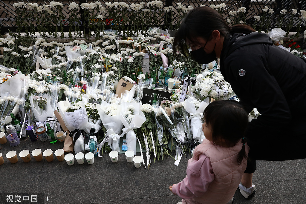 当地时间2022年10月31日，韩国首尔，一名女子在踩踏事件现场附近的街道吊唁遇难者。