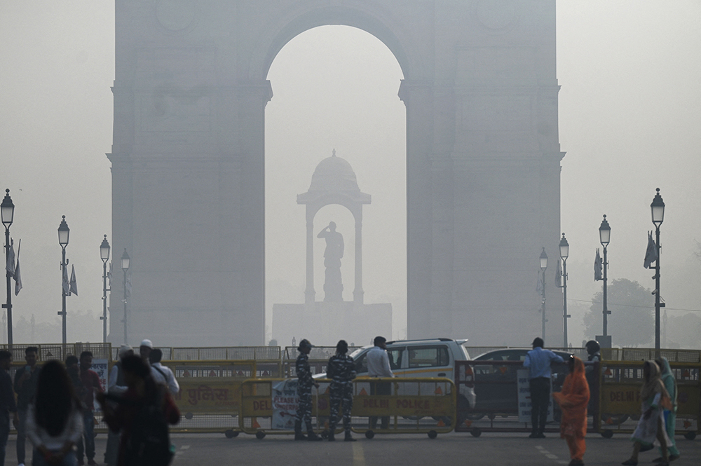 当地时间2022年11月3日，印度新德里，雾霾弥漫，行人在印度门附近的一条道路上行走。视觉中国 图