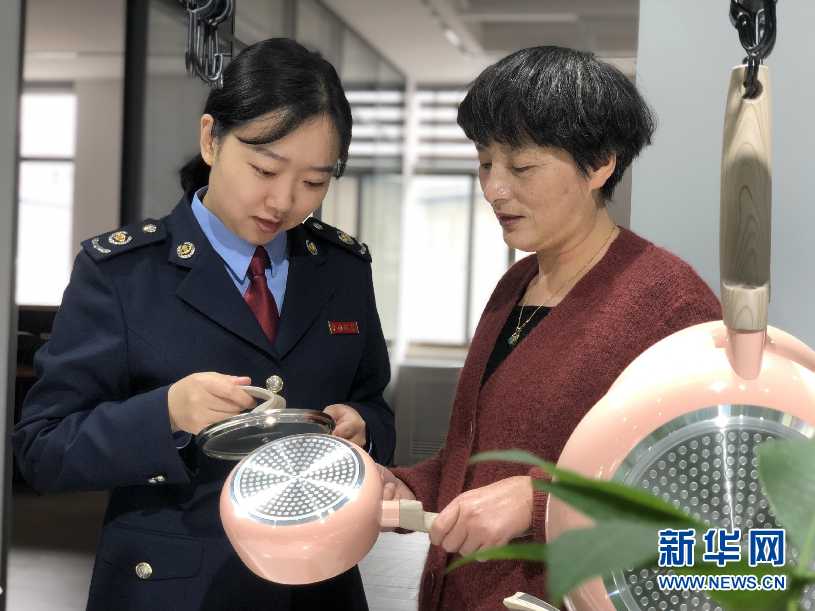 税务人员与宁波喜尔美厨房用品有限公司工作人员交流。新华网发