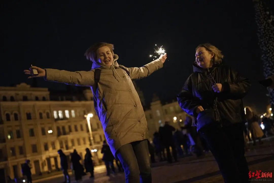 乌克兰基辅，在午夜宵禁前，一名女子手持烟火在索菲亚广场跳舞