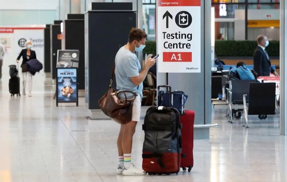 英国伦敦希思罗机场5号航站楼国际旅客抵达区，一名乘客站在新冠检测中心的标志前 图源：外媒