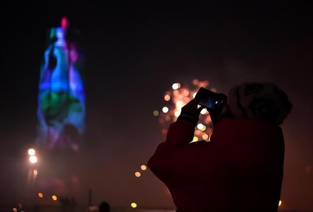 1月21日晚，市民在郑州市郑东新区千玺广场附近观看灯光秀。新华社记者 李嘉南 摄