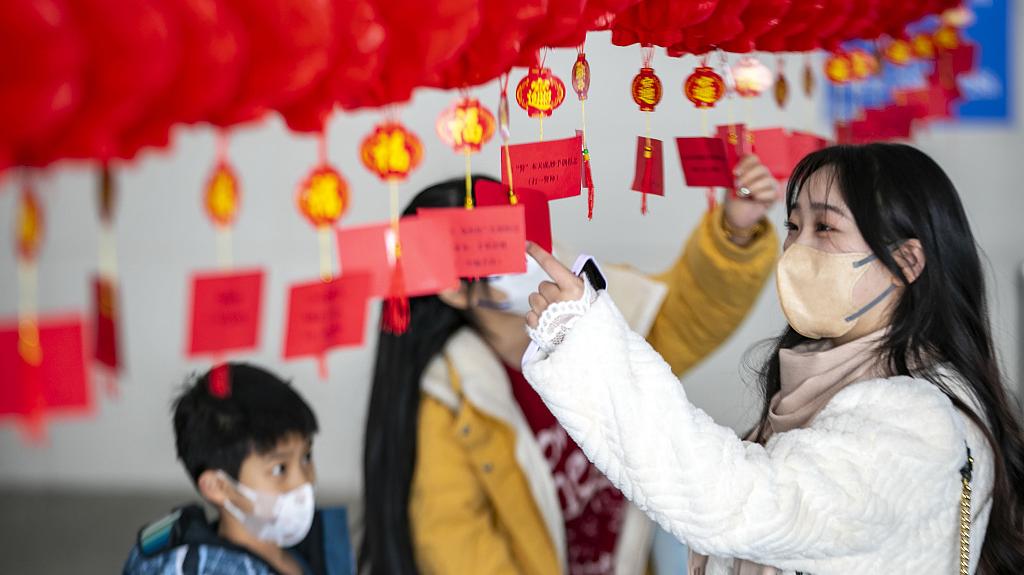 2023年2月3日,江苏泰州站候车厅内,旅客在猜以法治文化为主题的灯谜。视觉中国 图