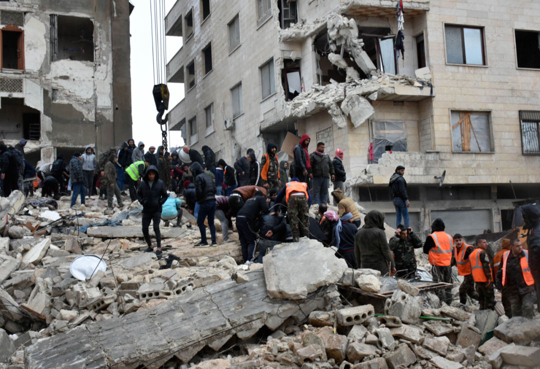 2月6日，人們在敘利亞哈馬省一處倒塌的建築上進行救援。  新華社發