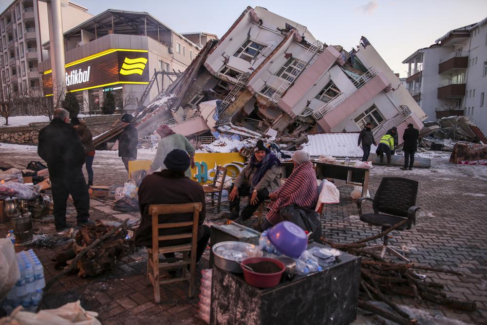 当地时间2月8日，土耳其南部阿德亚曼省格尔巴舍，人们在倒塌的建筑物旁。图片来源：美联社