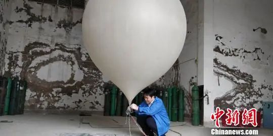 資料圖：貴陽市高空氣象探測站高級工程師閔昌紅正在為探空氣球灌裝氫氣。曾實 攝