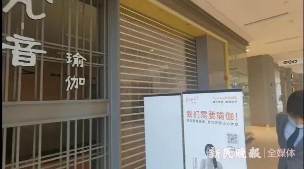 凯德晶萃广场物业已派人(图中打领带者)到该店门口值守,非经同意,店内物品不能拿出。新民晚报记者 罗水元 摄