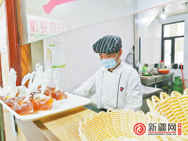 在米东南路街道兴业社区的餐饮店,店主邵明周在制作肉夹馍。(全媒体记者宋建华摄)