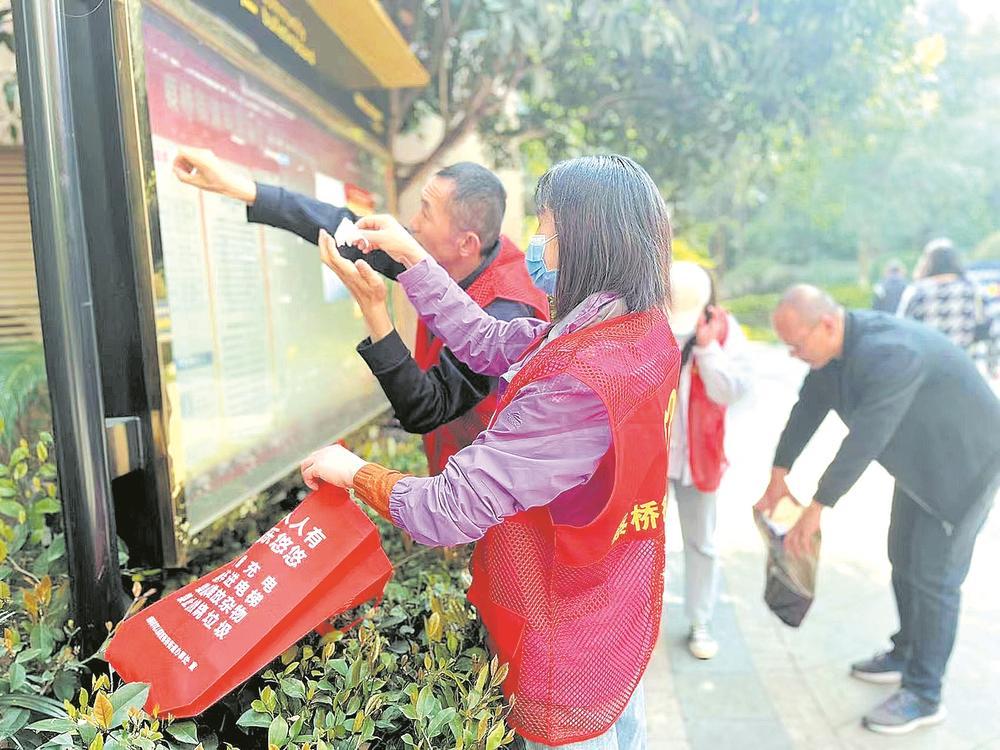 志愿者清理宣传栏上的“牛皮癣”