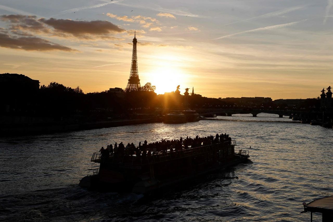 当地时间2021年10月13日，法国巴黎，日落时分一艘船驶过埃菲尔铁塔前的塞纳河。图/视觉中国