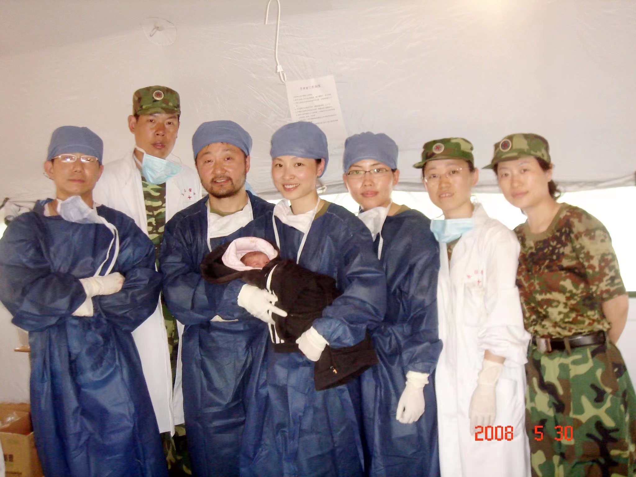 十五年前医疗队与第一个在帐篷医院中诞生的 “长征宝宝”（左四为刘晓军、右三为羊海琴）