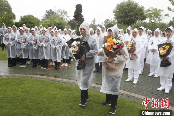 在漫天大雨中，家人、同事來到墓園緬懷吳孟超夫婦，一朵朵鮮花寄託著他們的思念。　
