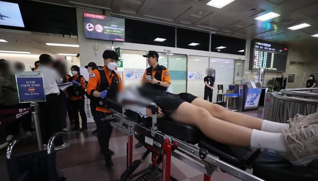 飞机在大邱国际机场紧急降落后,有身体不适者被担架抬走。图源:韩媒