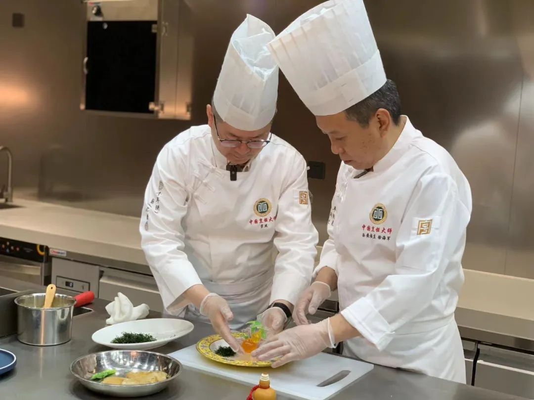 △李杰(左)与徐海军为西安发布记者还原讲述长安葫芦鸡的制作与糖艺装饰过程。