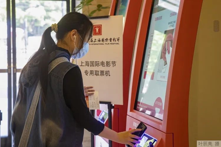 在大光明电影院,观众在专用取票机前扫码取票。