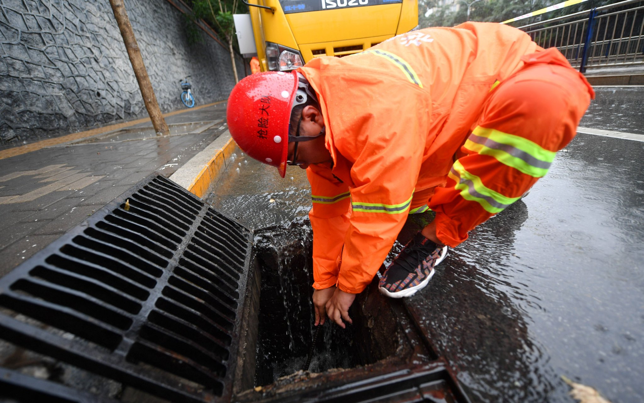 7月22日，北京排水集團搶險大隊防汛人員在雨中清理排水設施。新京報記者 王貴彬 攝