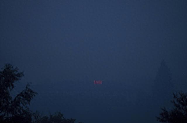 當地時間2023年8月20日，加拿大坎盧普斯，透過濃濃的野火煙霧，可以看到酒店屋頂上的霓虹燈。視覺中國 圖