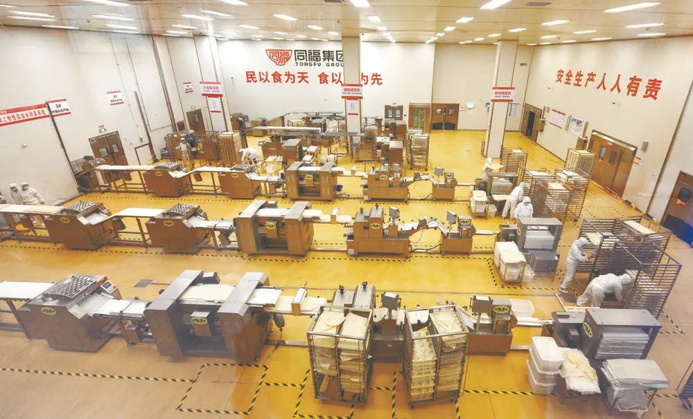 在同福大健康食品城中央厨房现代化的生产车间,工作人员在生产面点。