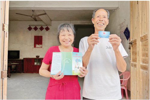 　　江西省兴国县良村镇良村村一对农民夫妇站在家门口展示自己的社保卡和城乡居民养老保险政策宣传单。　余春凤　摄