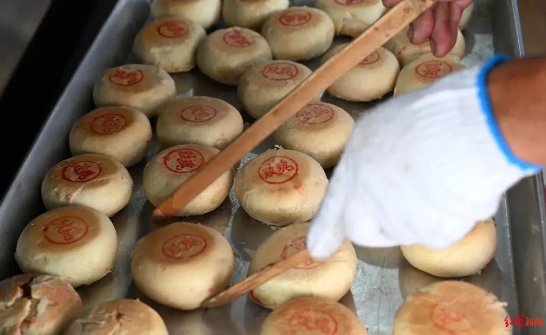 ▲制作老式月饼的师傅正将月饼从烤箱取出