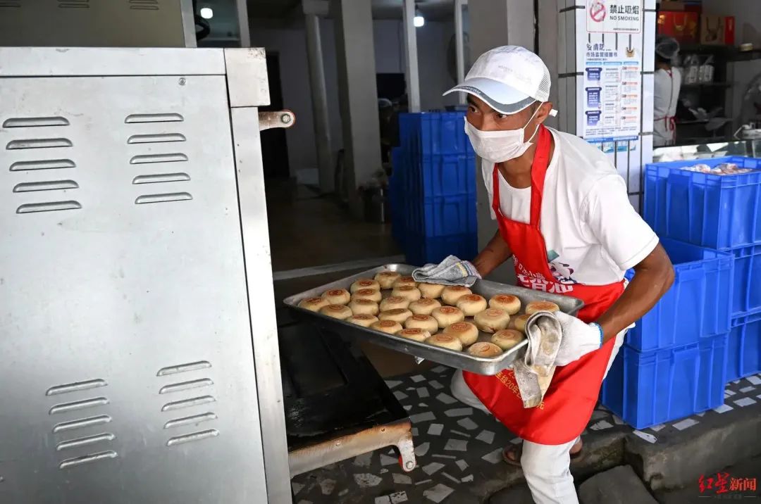 ▲制作老式月饼的师傅正将月饼从烤箱取出