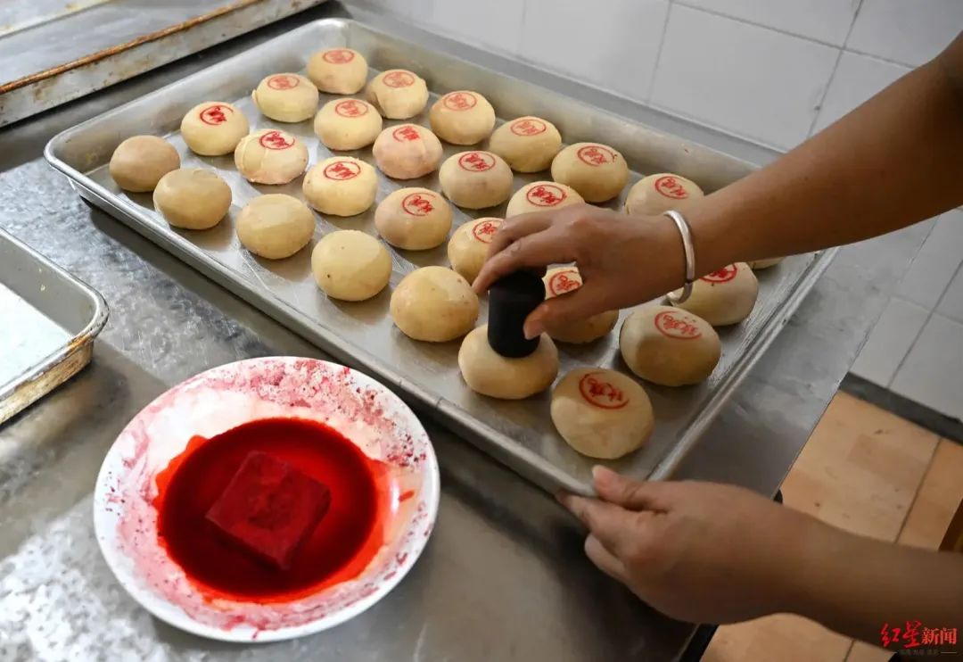 ▲工作人员在月饼上盖上红印,区分品种