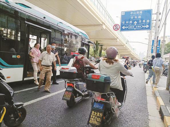 在滬閔路龍漕路的漕河涇公交站(上圖),白線畫出的“安全島”內非機動車可隨意穿行。陳浩 攝