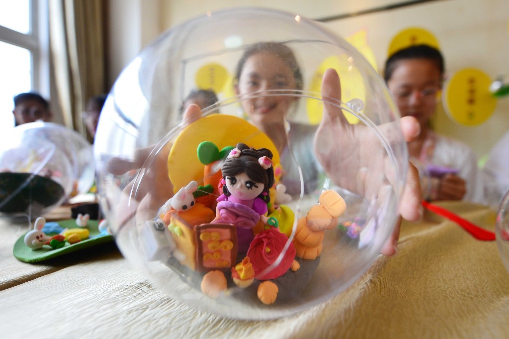 9月27日,在山东省青岛市市北区杭州路小学民俗迎中秋活动上,一名学生展示制作的月亮花灯。王海滨 摄