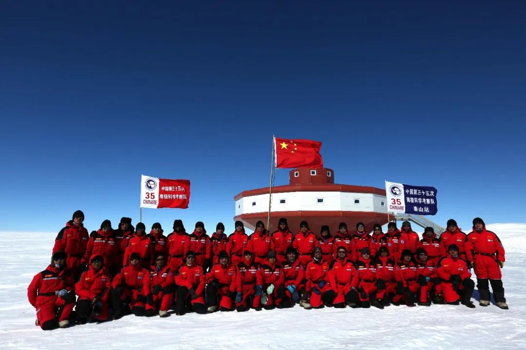 这是2018年12月26日,中国第35次南极科学考察队内陆队(泰山队和昆仑队)队员在泰山站主体建筑前升国旗合影。