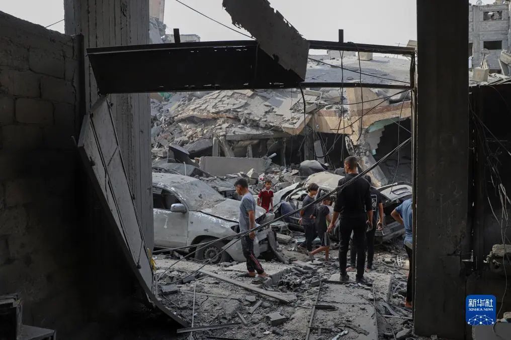 10月9日，在加沙城，人们查看被以色列空袭炸毁的建筑废墟。新华社发（里泽克·阿卜杜勒贾瓦德摄）