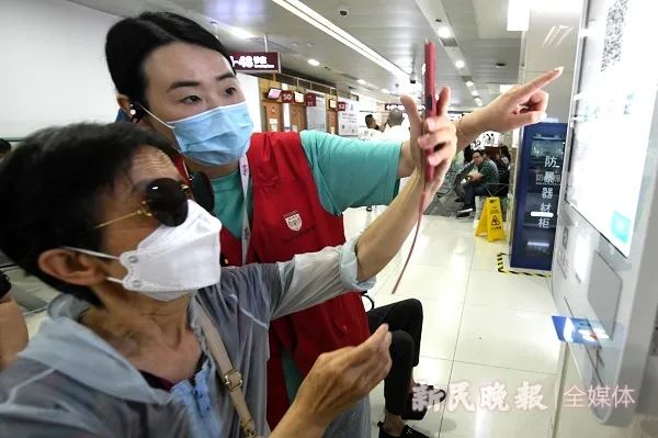 华山医院的志愿者帮助老人进行电子付费和线上挂号等服务